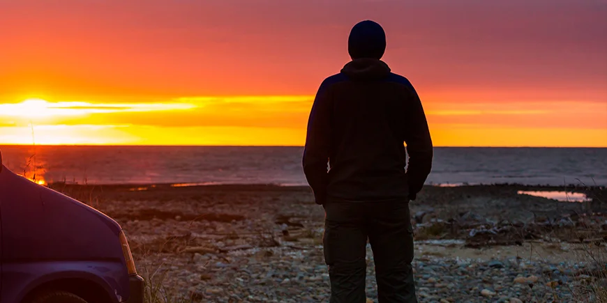 Man geniet van zonsondergang aan het water in Nieuw-Zeeland