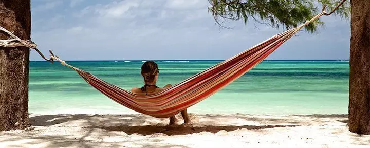 Vrouw ligt in hangmat op het strand van Zanzibar