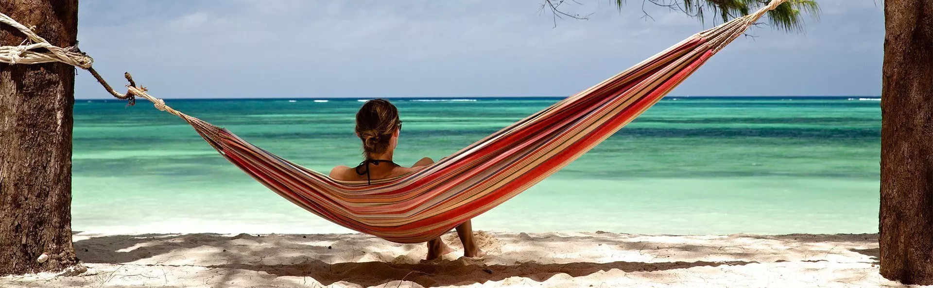 Vrouw ligt in hangmat op het strand van Zanzibar